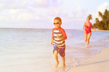 Naklejka premium mother and son running in water on beach