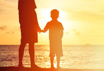 Fototapeta premium silhouettes of father and son holding hands at sunset