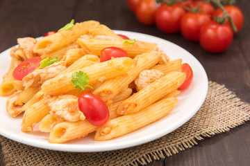 Penne pasta in tomato sauce with chicken on a wooden table