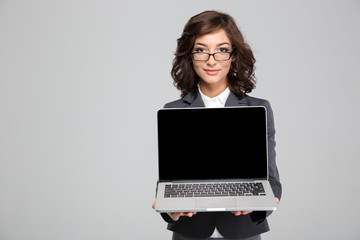 Young office worker holding laptop in front of herself