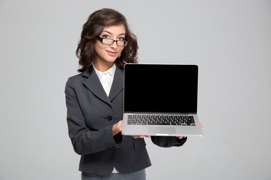 Confident pretty female showing blank laptop computer screen