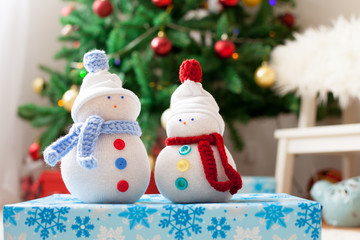 Two handmade snowmen with Christmas background on white fur