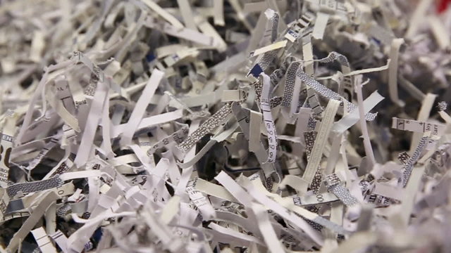 Shredded Paper Pans Slow. camera pans right in slow motion and then pans left in slow motion on a stack of shredded business paper on a red background
