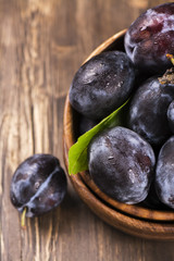 Autum or harvest concept: wooden bowl full of ripe plums. Selective focus