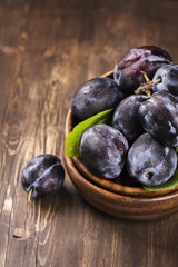 Autum or harvest concept: wooden bowl full of ripe plums. Selective focus