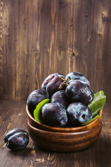 Autum or harvest concept: wooden bowl full of ripe plums. Selective focus