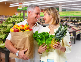 Senior couple with grocery bag of vegetables.