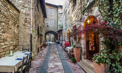 Fototapeta na wymiar Romantic dinner place in a beautiful alley in the ancient town of Assisi, Umbria, Italy