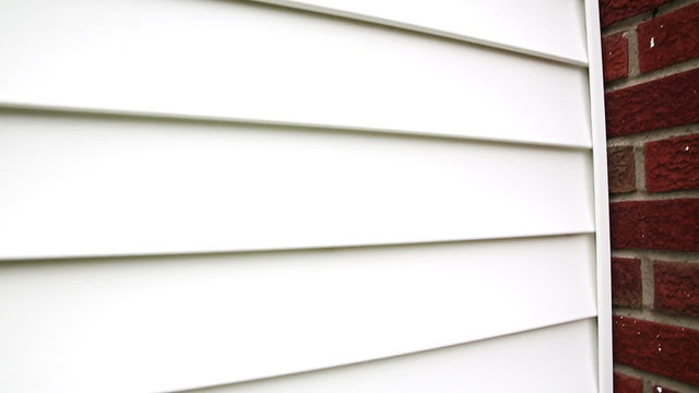 Vinyl Siding to Brick Chimney. camera pans and rises right on vinyl siding and a brick chimney
