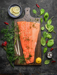 Perfect salmon fillet on rustic cutting board with fresh ingredients for tasty cooking