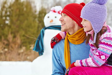 Father and daughter with snowman