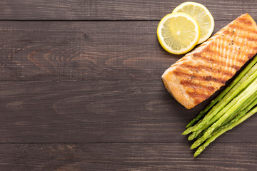 Grilled salmon with lemon, asparagus on wooden background