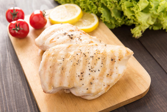 Marinated grilled chicken breasts on the wooden table