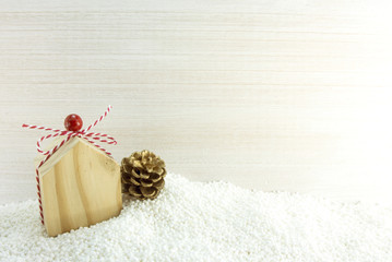 wood home gift and pine cone on snow ground