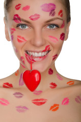 beautiful woman with kisses on face holding heart in teeth