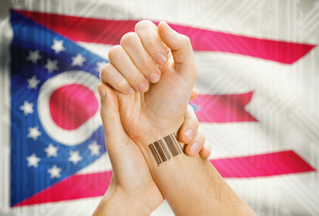 Barcode ID number on wrist and USA states flags on background - Ohio