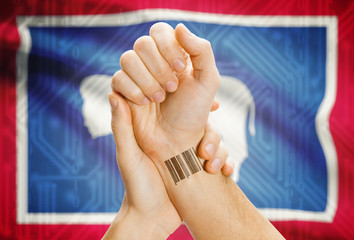 Barcode ID number on wrist and USA states flags on background - Wyoming