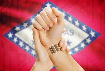Barcode ID number on wrist and USA states flags on background - Arkansas