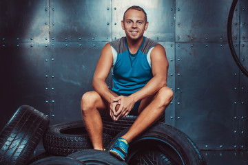 Sportsman sitting on the tire machine. Concept of CrossFit, health and strength.