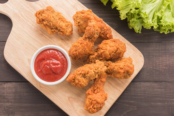 Fried chicken drumstick and ketchup on wooden table