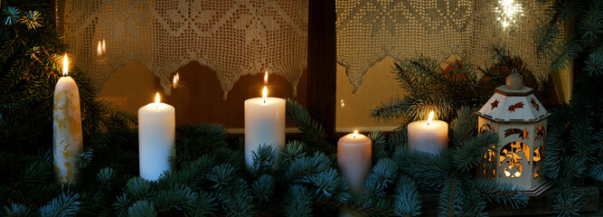 adventlich/weihnachtlich geschmücktes Fenster mit Kerzen, Tannenzweigen und Laterne,...