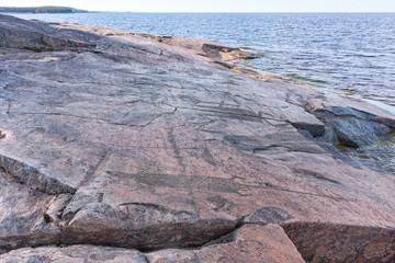 View on Onega Lake shore with ancient petroglyphs (rock engravings of 4th-2nd millennia BC) that depict demon figure, muskrat and swan carved on granite. Besov Nos cape, Karelia Republic, Russia.
