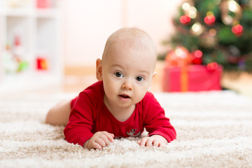 Funny baby in Santa Claus clothes with xmas tree