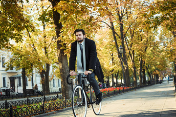 young caucasian businessman riding bicycle