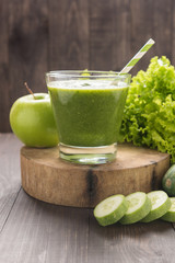 Healthy green vegetables and green fruit smoothie on rustic wood