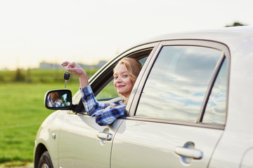 woman looking out of the car window and holding a key
