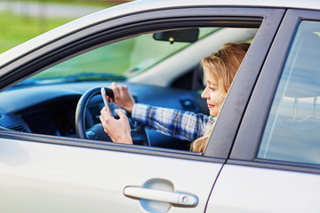 young woman driving a car and using phone