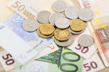 business, finance, investment, saving and cash concept - close up of euro paper money and coins on table