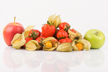 Red and green apples with orange physalis and red strawberries on white background.