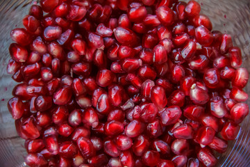 Pomegranate seeds, juicy fruit in a glass container.