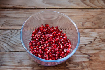 Pomegranate seeds, juicy fruit in a glass container.