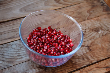 Pomegranate seeds, juicy fruit in a glass container.