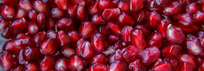 Pomegranate seeds, juicy fruit in a glass container.