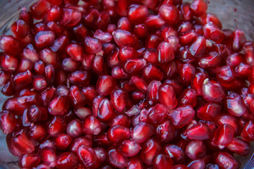 Pomegranate seeds, juicy fruit in a glass container.