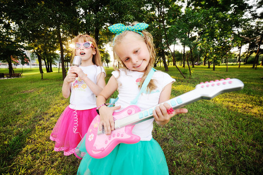 Two little girls play guitar and sing
