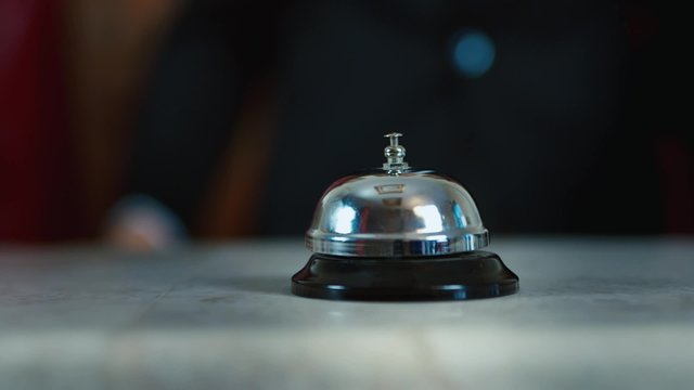 Hand strikes the bell on hotel reception