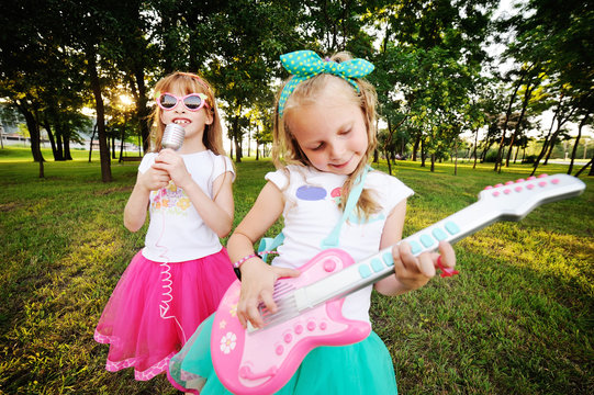 Two little girls play guitar and sing