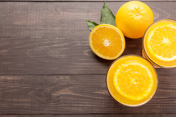 Fresh orange juice and oranges on wooden background