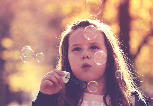 Little girl making soap bubbles