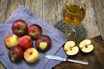 Still-life composition with red-ripe apples and juice in a glass on old wooden background. Grunge style. Delicious fruit. Image of natural materials.