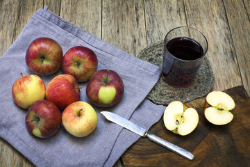 Still-life composition with red-ripe apples and juice in a glass on old wooden background. Grunge style. Delicious fruit. Image of natural materials.