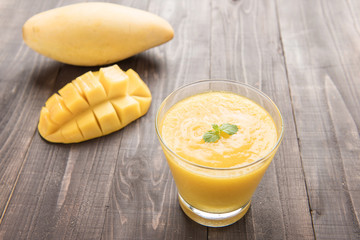 Mango smoothie and yellow mango on wooden table