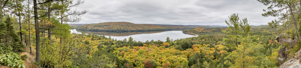 Fototapeta na wymiar Panorama Looking Out Over a Lake Surrounded by Forest in Autumn