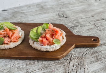 Whole grain tortilla with avocado and salmon, served on a wooden board, bright wooden surface. Rustic style. Healthy food