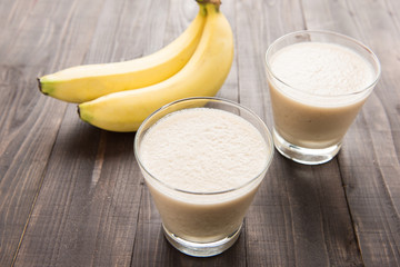 Banana smoothie and fresh banana on wooden table