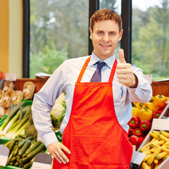 Verkäufer im Supermarkt hält Daumen hoch